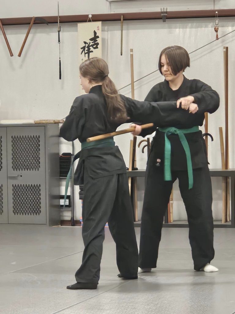 2 young women practicing bojutsu Japanese stick art