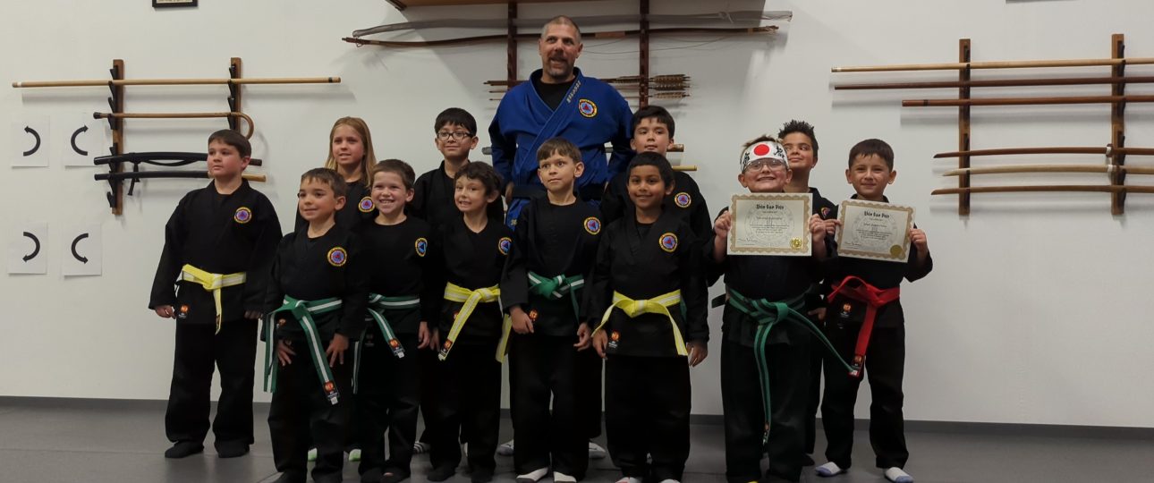 A group of kids with their martial art instructor. The kids have just passed belt rank exams.